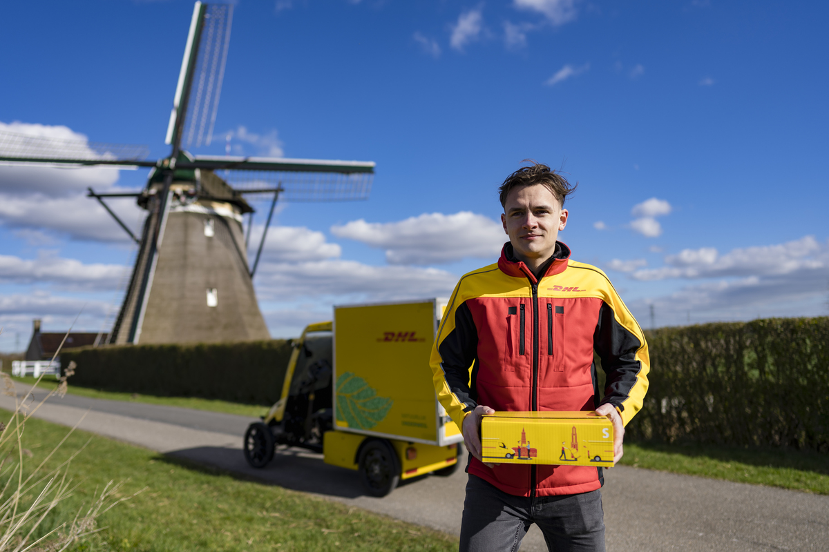 DHL Bezorgfiets op een dijk met windmolen